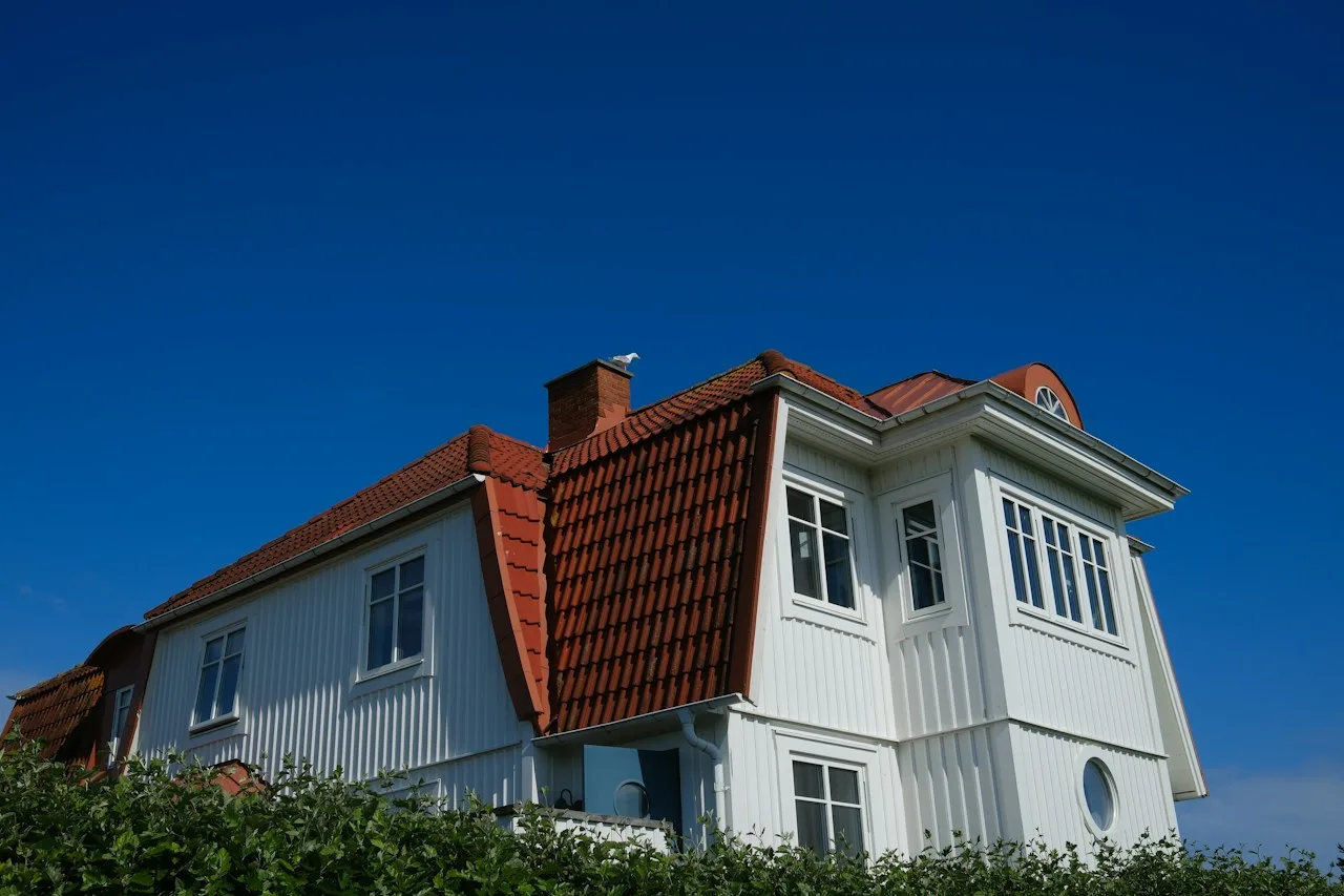 Stor hvit bolig med flere etasjer og rødt tak